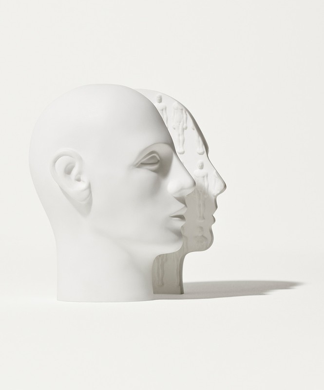 Side view of two white mannequin heads, one slightly offset and partially overlapping the other against a bright white background.