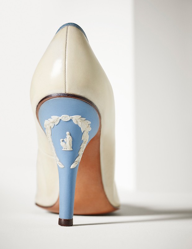 Close-up of a white leather high-heel shoe with a light blue heel adorned with a decorative white sculptural figure.