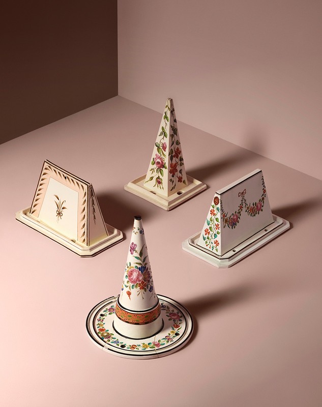 Four decorative objects with floral patterns are arranged on a pink surface, creating a visually appealing and artistic still life.