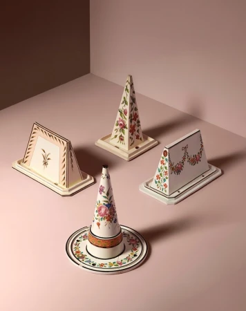 Four decorative objects with floral patterns are arranged on a pink surface, creating a visually appealing and artistic still life.