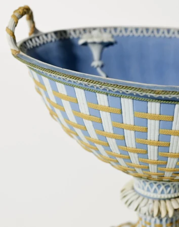 Elegant light blue and white footed bowl featuring woven pattern and delicate ornamentation on a clean white background.