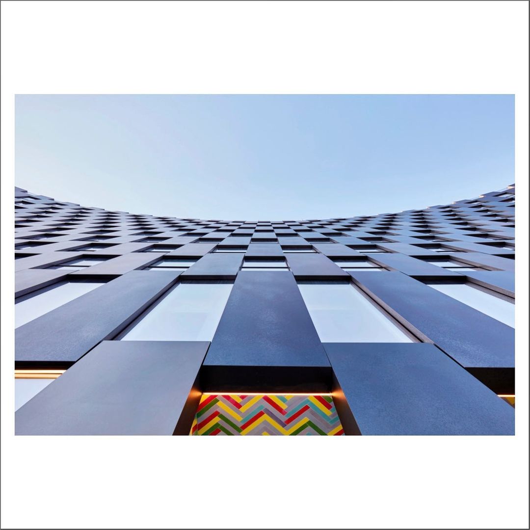 Architectural photograph of a blue building facade with patterned windows and a blue sky, showcasing modern building design and urban architecture.