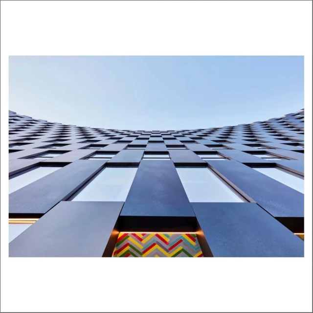 Architectural photograph of a blue building facade with patterned windows and a blue sky, showcasing modern building design and urban architecture.