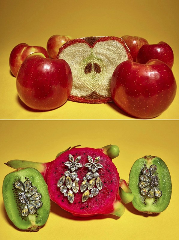 Still life of fresh red apples and a half-apple beaded clutch; sparkling earrings placed on kiwi and dragon fruit halves on yellow.