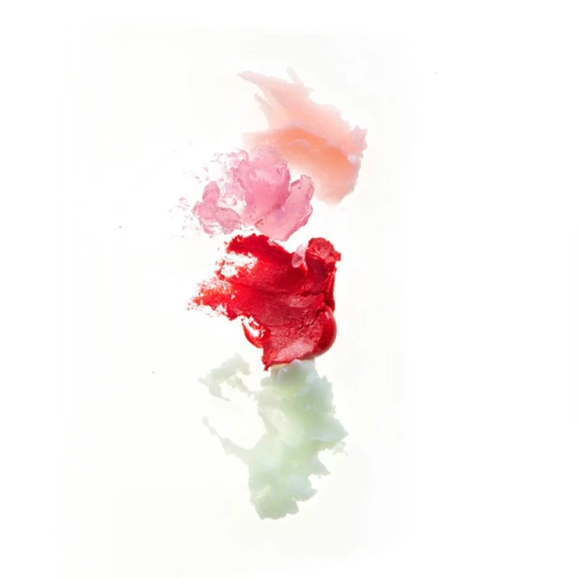 Close-up of a vertical column of lipstick smears in peach, pink, and red on a white background, with a partial reflection.