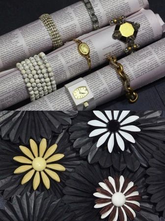 Close-up of bracelets arranged on rolled newspapers and black paper flower sculptures styled by Thomas Tomczak
