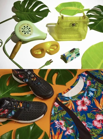 Flat lay of tropical props including monstera leaves, green hairdryer, translucent yellow handbag, sunglasses, and floral sportswear.
