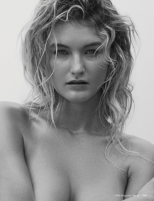 Close-up monochrome portrait of a woman with wet hair and a direct gaze against a plain backdrop.