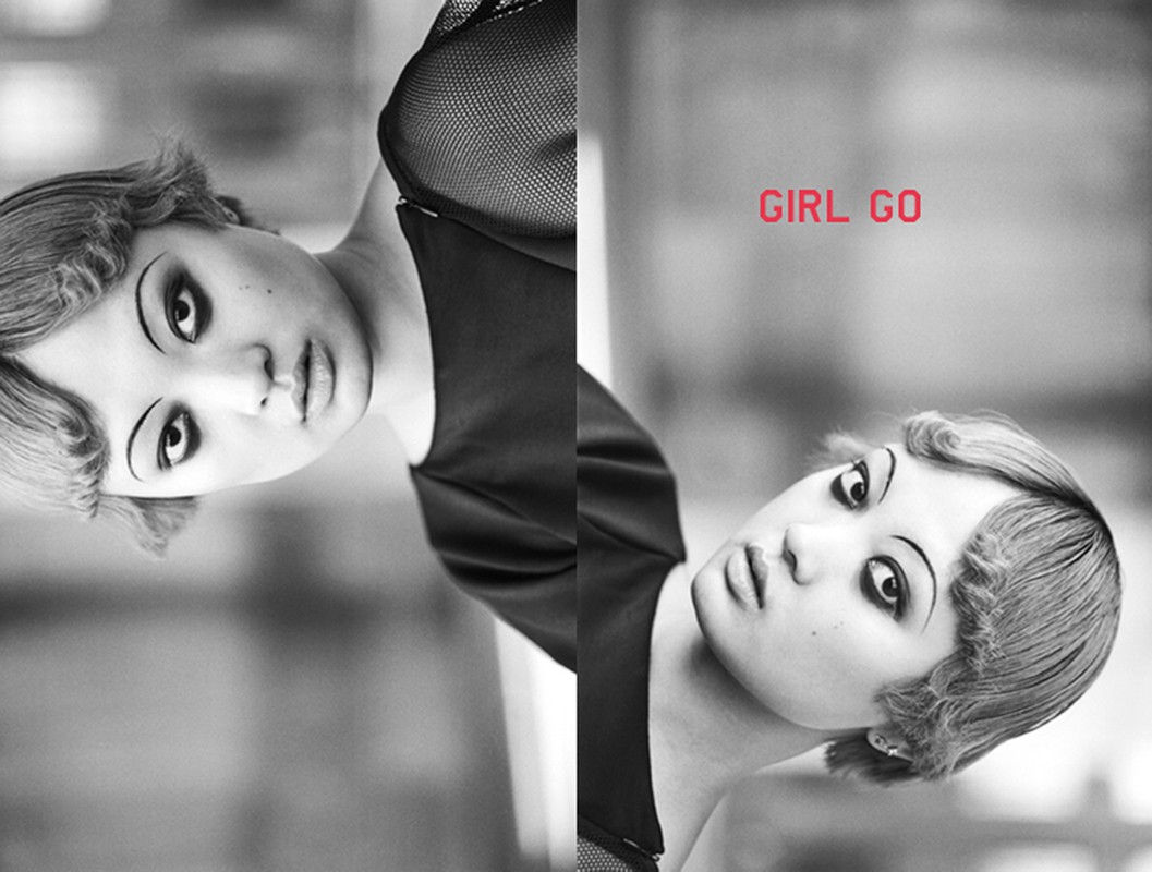 Monochrome portrait of a fair-skinned adult female with retro hairstyle and heavy makeup, reflected in vertical segments, with visible text.