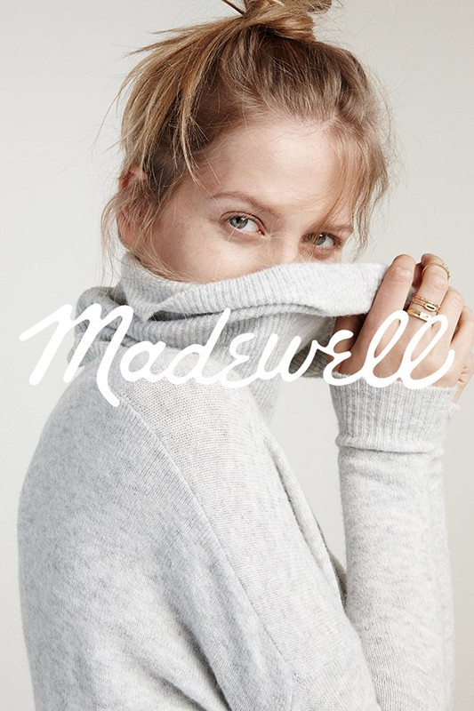 Close-up shot of a blonde woman with a high bun wearing a grey turtleneck sweater, partially covering her face, with the Madewell logo.