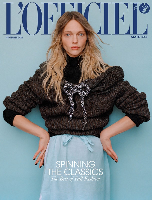 Fashion magazine cover featuring a model wearing a knit sweater and light blue skirt against a light blue background with the magazine logo.