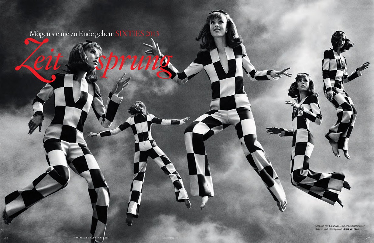 Fashion editorial shot of five women in black-and-white checkered jumpsuits, posing mid-air against a cloudy sky backdrop, 1960s-inspired.