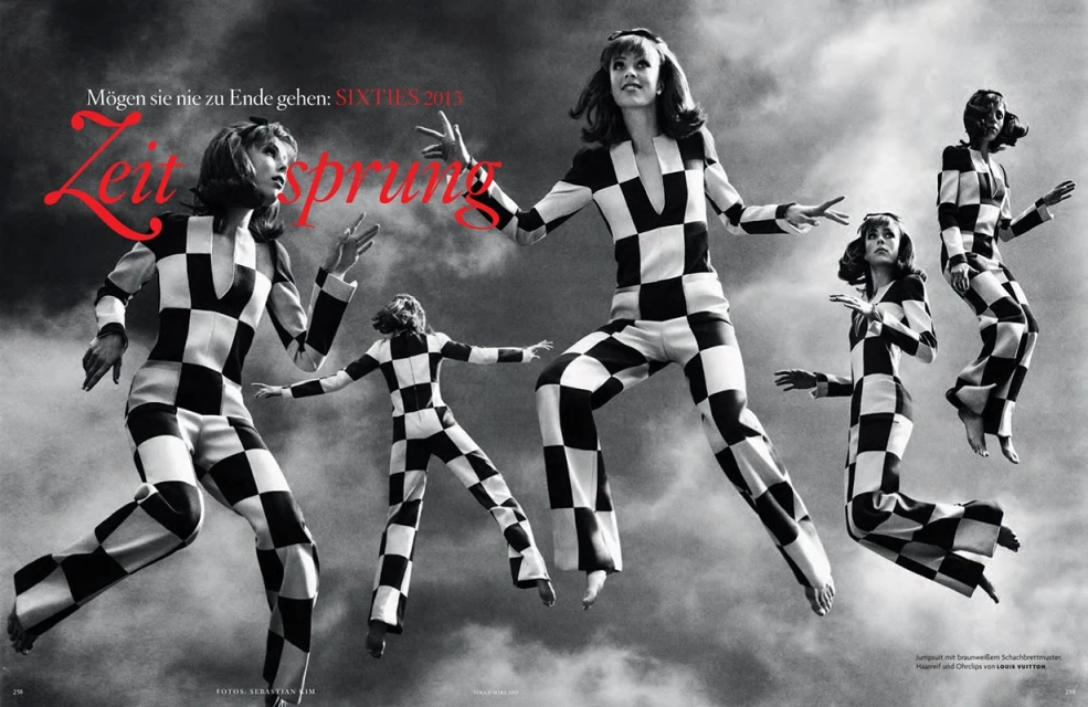 Fashion editorial shot of five women in black-and-white checkered jumpsuits, posing mid-air against a cloudy sky backdrop, 1960s-inspired.