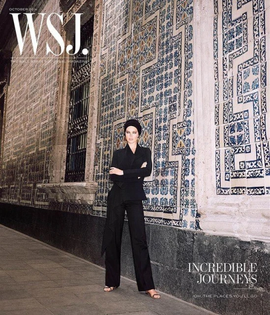 WSJ magazine cover featuring a woman in a black suit posing against a patterned tile wall on a city street in an outdoor shot.