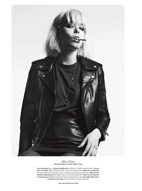 Black and white portrait of Alice Glass smoking, wearing a leather jacket and skirt, with short blonde hair and a silver necklace.