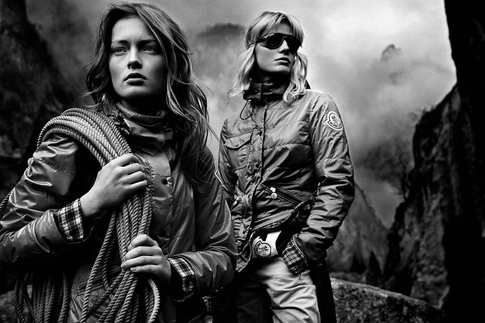 Two women in outdoor fashion with climbing rope against a misty mountain backdrop, creating a striking black and white editorial image.