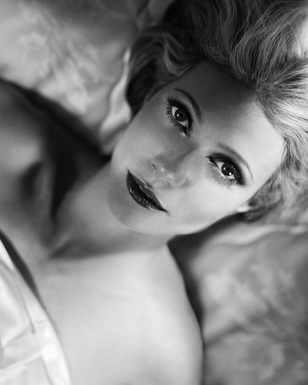 Close up monochrome portrait of blonde woman lying down looking up captured by photographer Vincent Peters