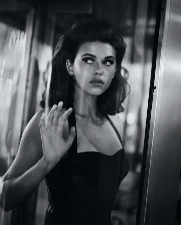 Black and white portrait of a woman looking sideways with her hand pressed against a glass door or window