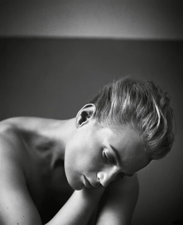 Black and white portrait of a woman with short blonde hair looking down thoughtfully by photographer Vincent Peters