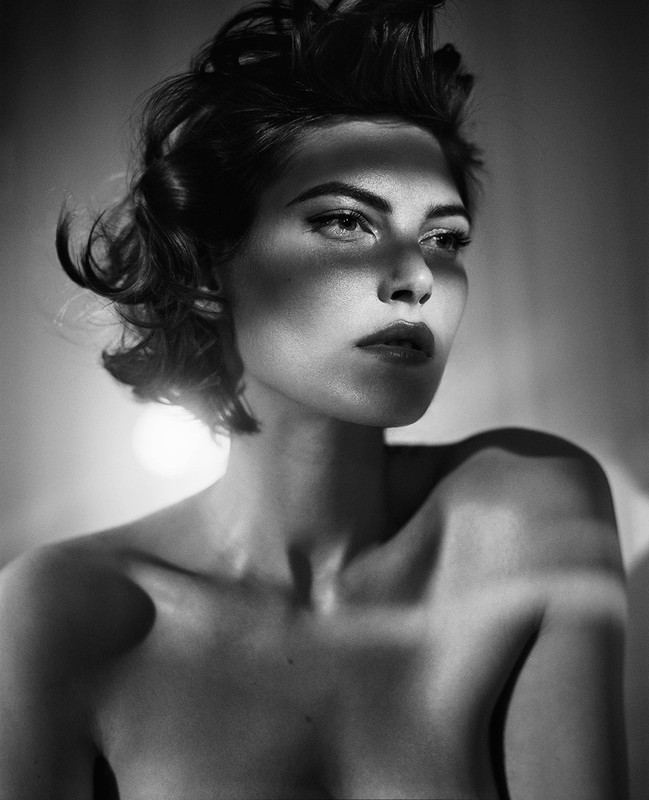 Monochrome portrait of a woman with dark wavy hair and dramatic shadow bands across her face by Vincent Peters