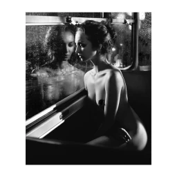 Black and white portrait of a woman seated by a rain-streaked window with her reflection visible in the glass.