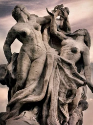 Dramatic low-angle photograph of a monumental stone sculpture depicting entangled human figures against a muted sky