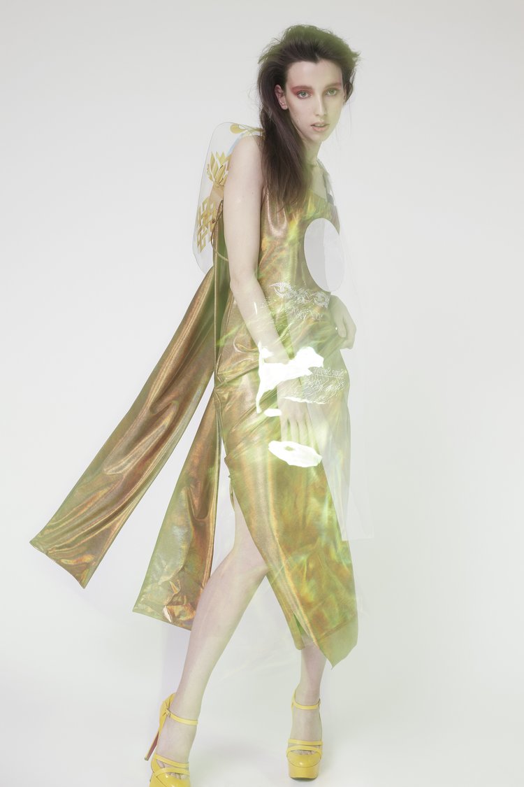 Model in a shiny metallic gold dress and yellow platform heels posing against a bright seamless white background