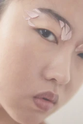 Close-up portrait of a woman with pale pink flower petal-like pieces arranged around her eyebrow and eye in Los Angeles