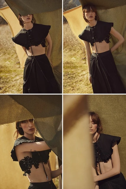 Fashionable woman in black two-piece outfit with lace detailing posing outdoors on a sunny day with cloth backdrop.