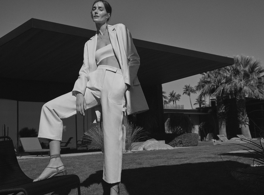 Model in white trouser suit and strapless crop top posing outdoors by Williams and Hirakawa.