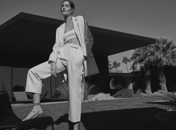 Model in white trouser suit and strapless crop top posing outdoors by Williams and Hirakawa.