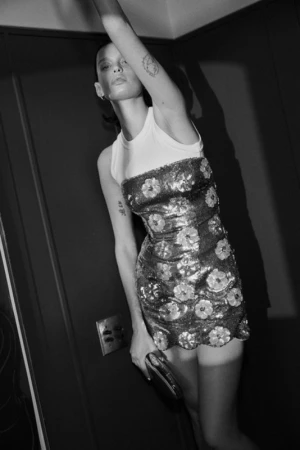 Black and white portrait of a woman in a sequined floral mini dress holding a small clutch, photographed by Williams + Hirakawa.