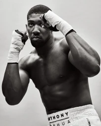 Anthony Joshua in boxing stance with white hand wraps and shorts against grey background by Williams + Hirakawa