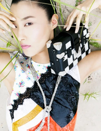 Close-up portrait of a model with pink lipstick posing next to a black and white checkered trunk bag in Los Angeles.