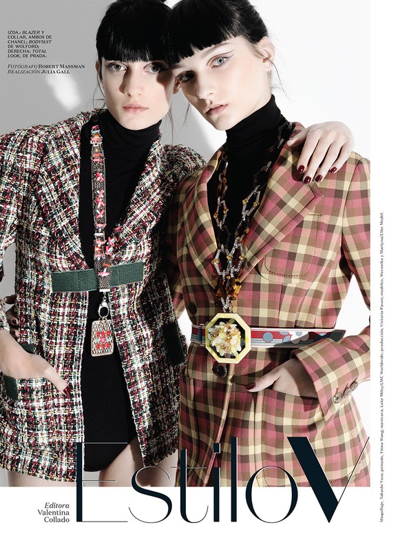 Two women in plaid blazers pose in a studio shot with a fashion editorial aesthetic, showcasing stylish outerwear and bold accessories.