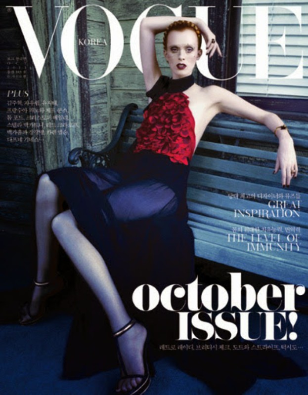 Vogue Korea cover featuring a fashion model in a red and black dress posing on a bench in front of a weathered wood building.