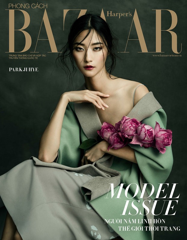 Fashion magazine cover featuring a model with dark hair, light skin, and a pink flower bouquet wearing a stylish green coat.