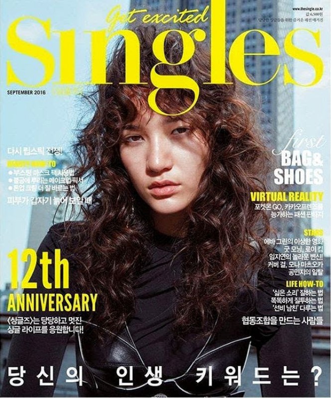 Magazine cover featuring a model with curly hair. The magazine title 'Singles' is prominently displayed in yellow on a blurred city background.