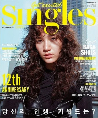 Magazine cover featuring a model with curly hair. The magazine title 'Singles' is prominently displayed in yellow on a blurred city background.