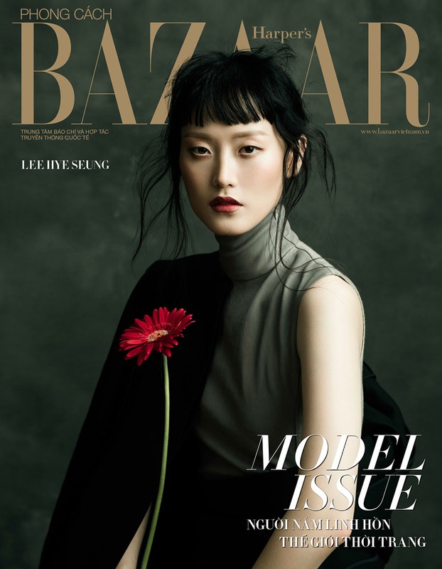 Harper's Bazaar magazine cover featuring an Asian woman model in a gray top and black jacket holding a red gerbera daisy.