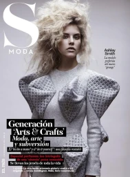 Model with voluminous blonde hair wearing a grey quilted dress with structured geometric shoulder accents.