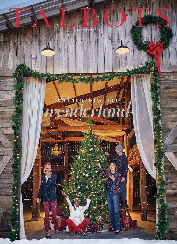 Talbots December 2023 holiday catalog cover featuring four people posing near a Christmas tree inside of a decorated barn.