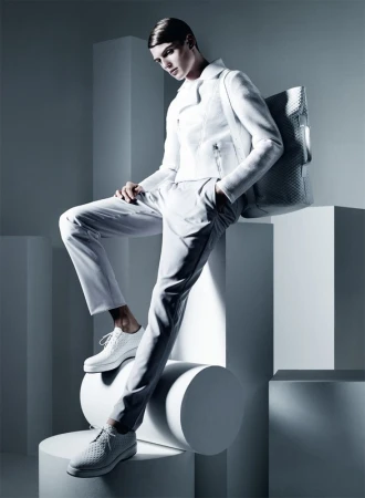 Model in white jacket and trousers posing on geometric studio blocks with a woven tote bag