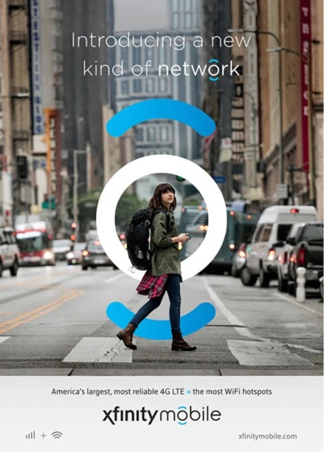 Young woman with backpack walks in city crosswalk; tall buildings and light traffic.  Xfinity Mobile advertisement.