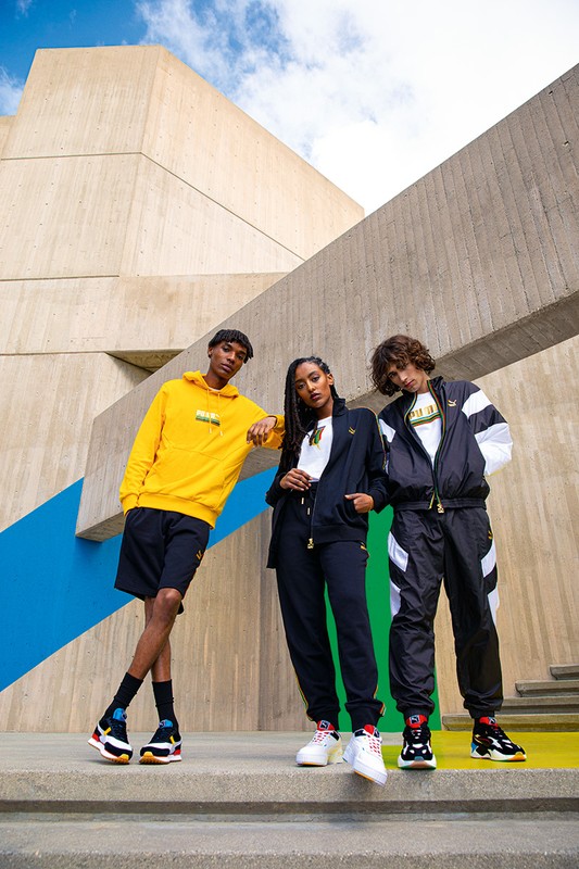 Three diverse individuals showcase athletic apparel in front of a modern concrete structure against a blue-sky backdrop.