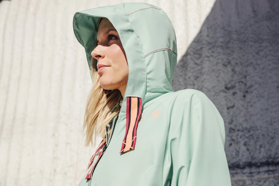 Blonde woman wearing a hooded jacket in outdoor light. Close-up shot of an adult female in a hooded jacket looking off-camera.