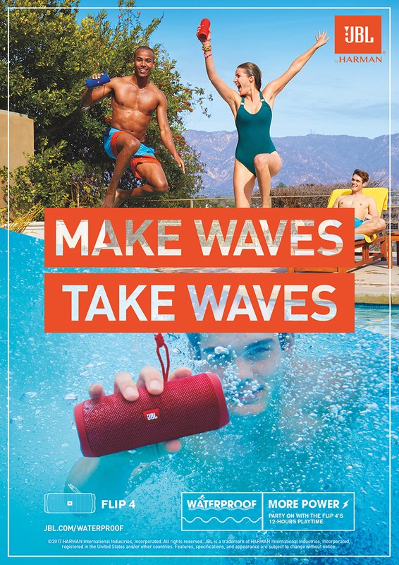An outdoor ad for JBL with three people by a pool, one underwater with a red Flip 4 waterproof portable speaker, promoting sound and music.