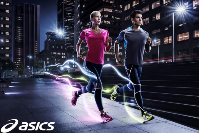 A woman and a man running in athletic wear in a nighttime city scene with graphic light trails and the Asics logo.