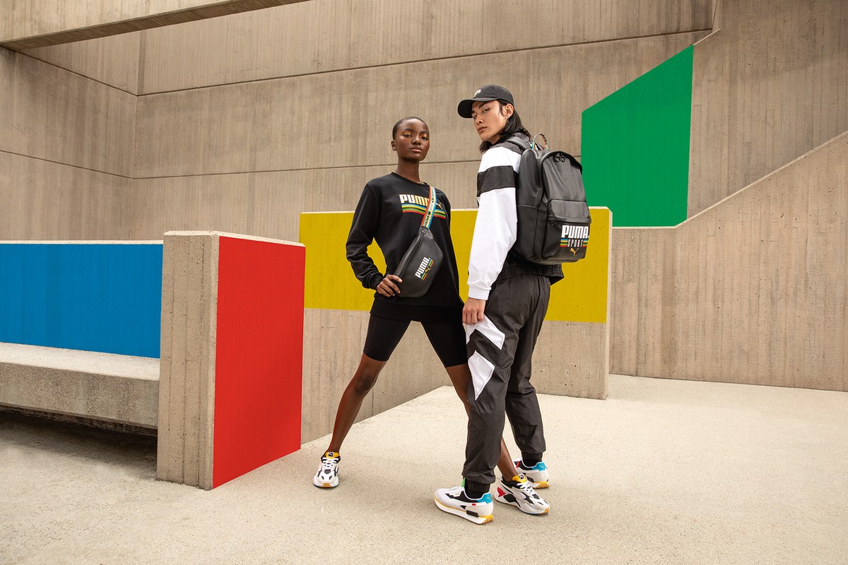 Two models showcasing Puma apparel and accessories outdoors against a colorful concrete wall. Fashion and sportswear concept.