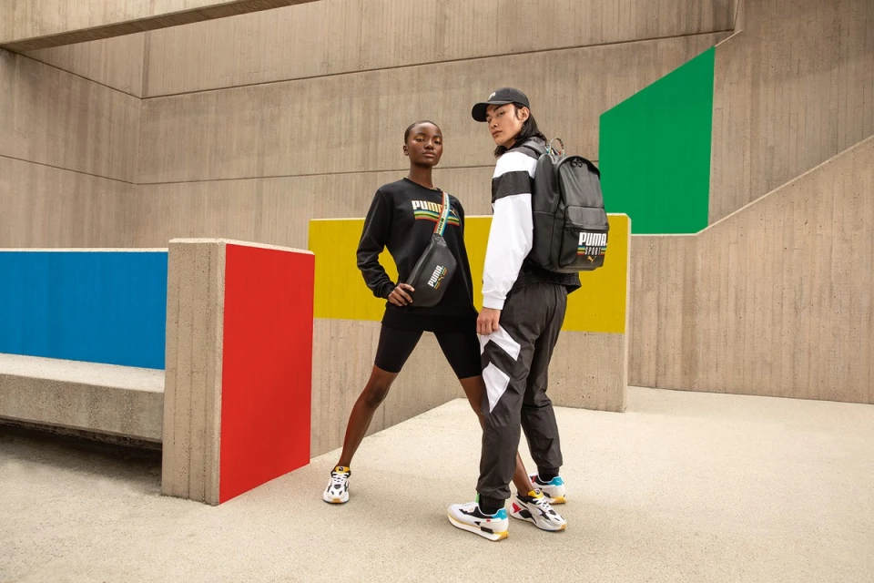 Two models showcasing Puma apparel and accessories outdoors against a colorful concrete wall. Fashion and sportswear concept.